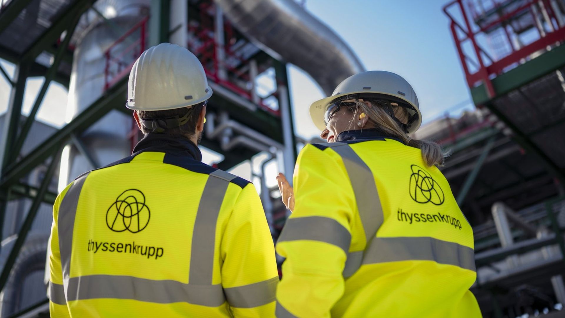 Mitarbeitende vor einer Industrieanlage