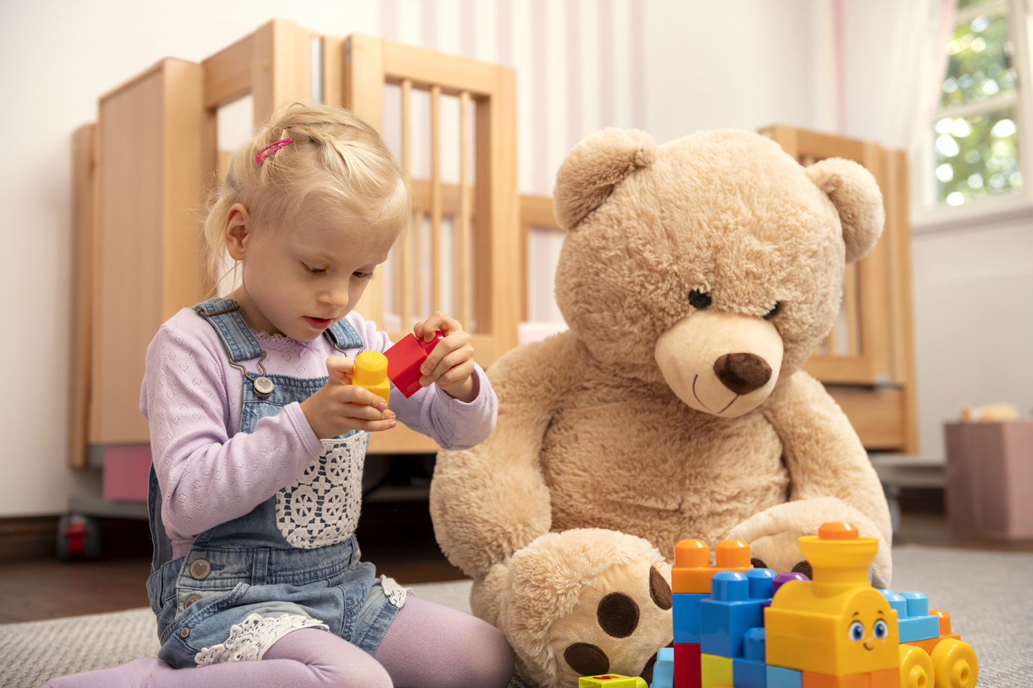 Mädchen und Teddy vor Kinderpflegebett EMMA