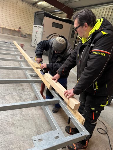 Holzbalken wird auf den Metallrahmen gelegt