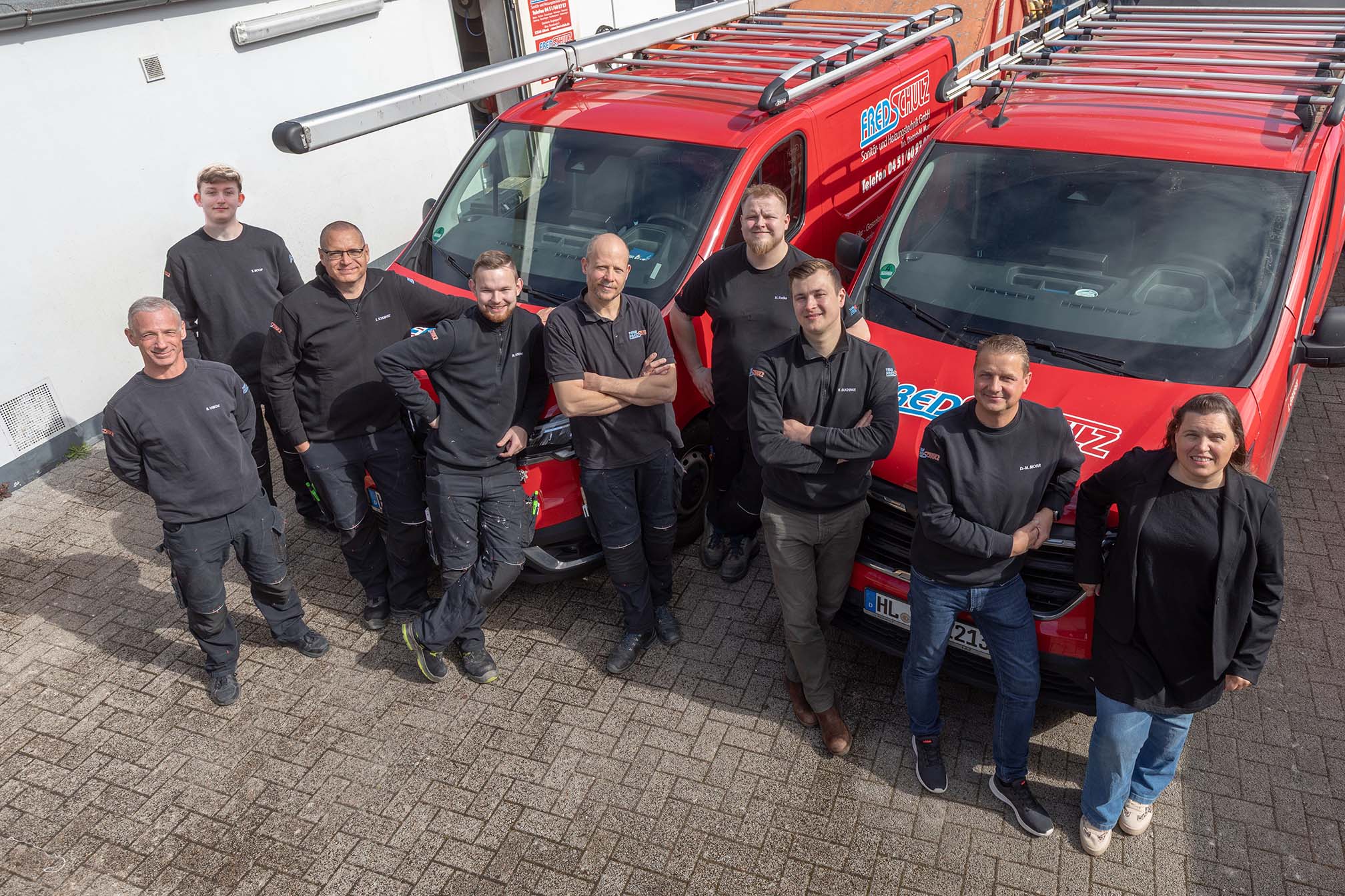 Team vor den Firmenfahrzeugen in Lübeck