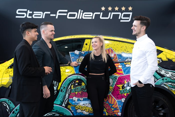 Teammitglieder vor foliertem Fahrzeug