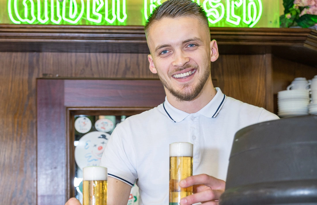 Kellner reicht Gläser Gilden Kölsch über die Theke