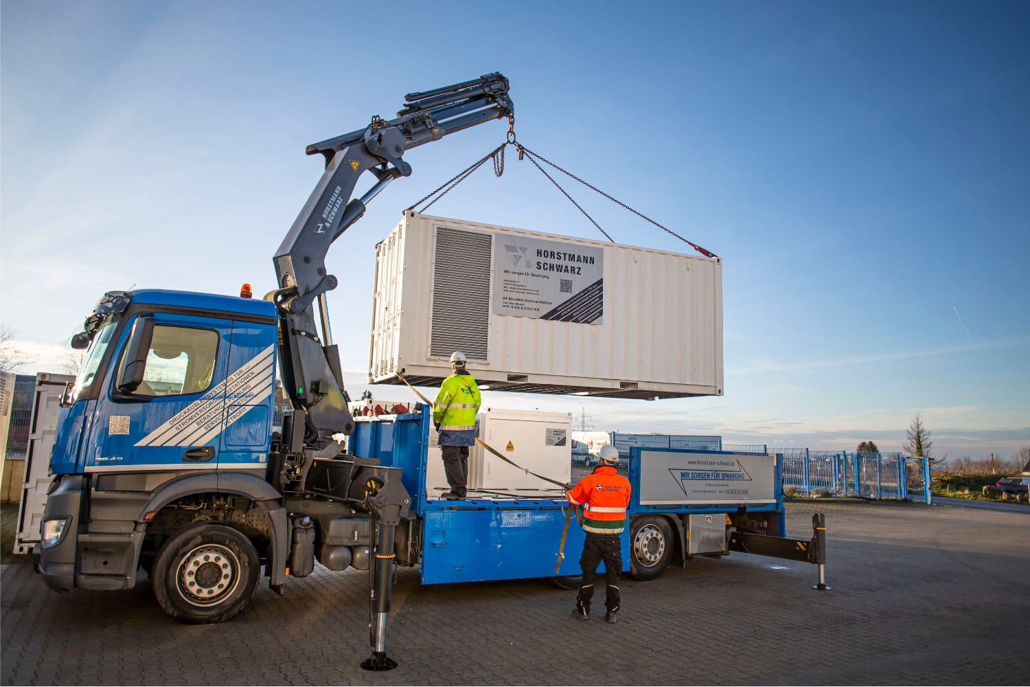 Transport einer 20-Fuß-Container-Trafostation mit LKW und Bordkran