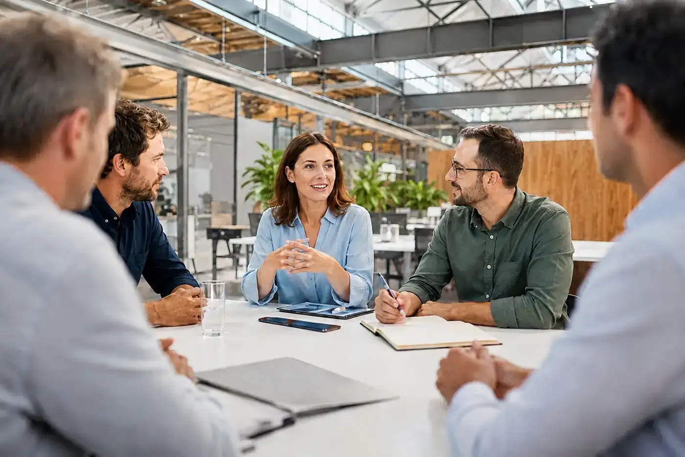 Team aus fünf Personen bei einer Besprechung in heller Bürolounge