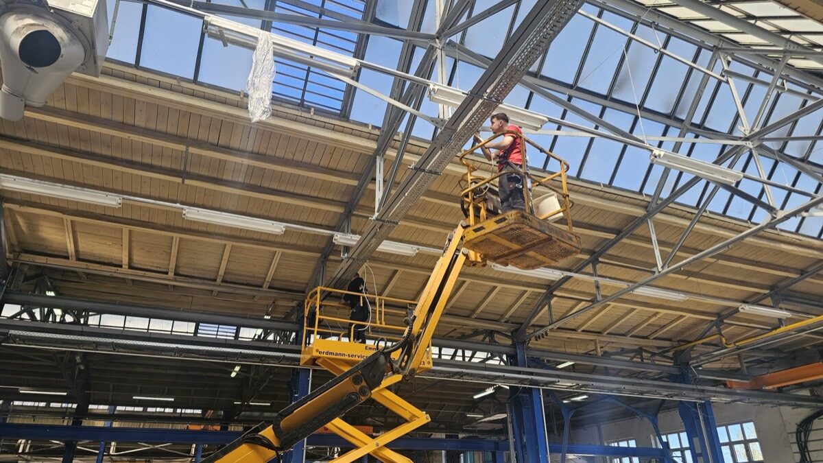 Monteur auf der Arbeitsbühne bei der Hallenbeleuchtung