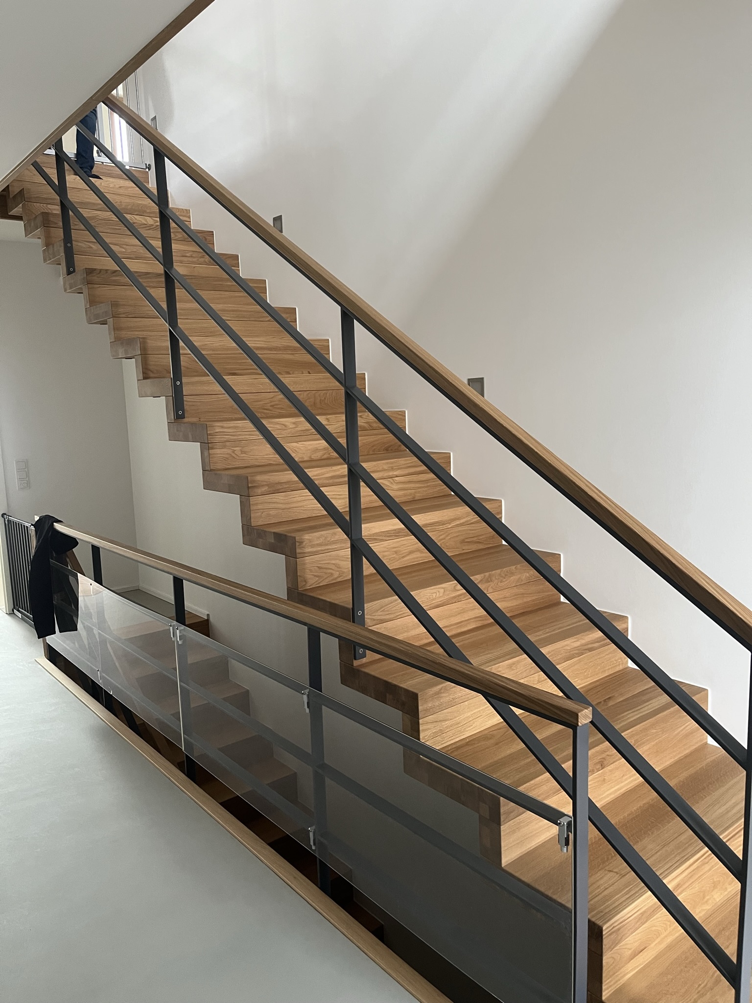 Bolzentragende Treppe mit Stahlgeländer und Massivholzhandlauf