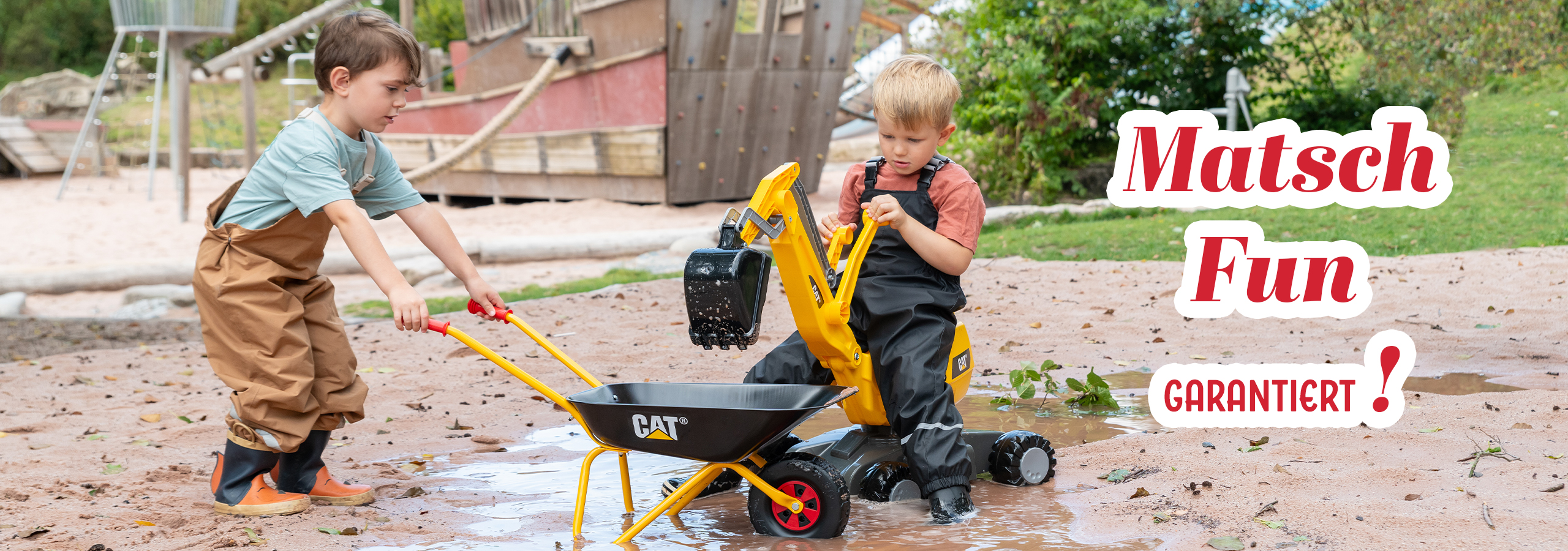 Kinder spielen im Matsch mit rolly toys Schaufelmaschine und Schubkarre