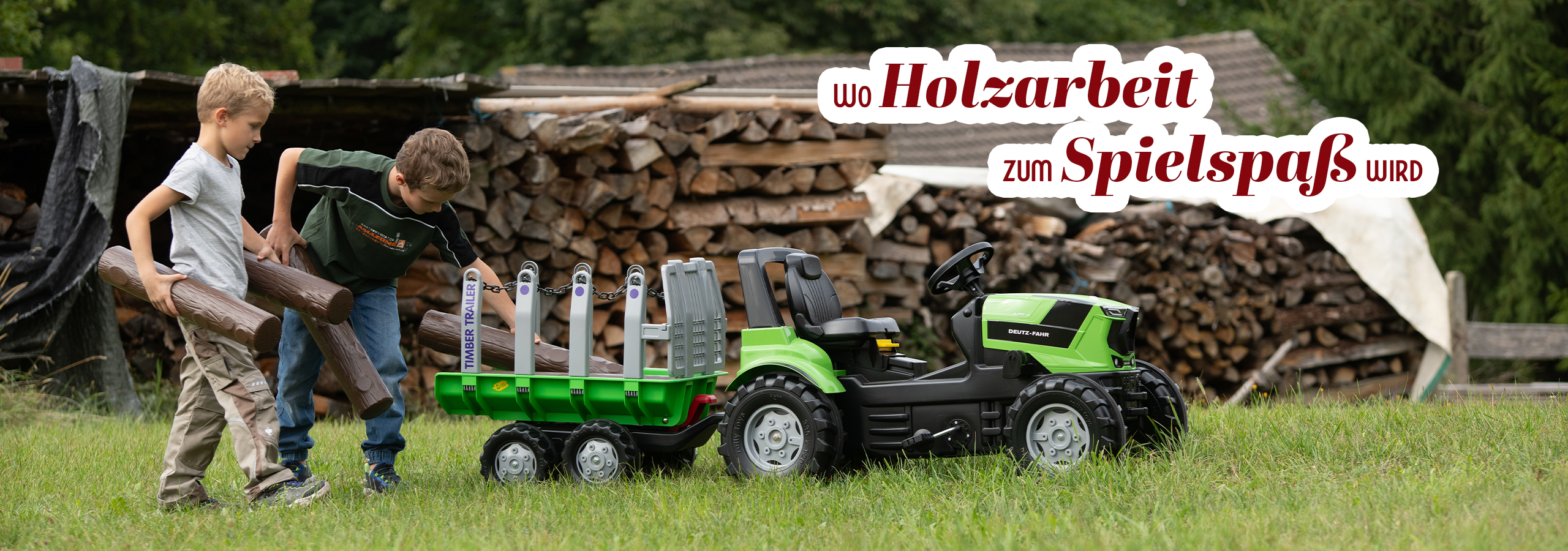 Pedaltraktor mit Holzstämmen beladen