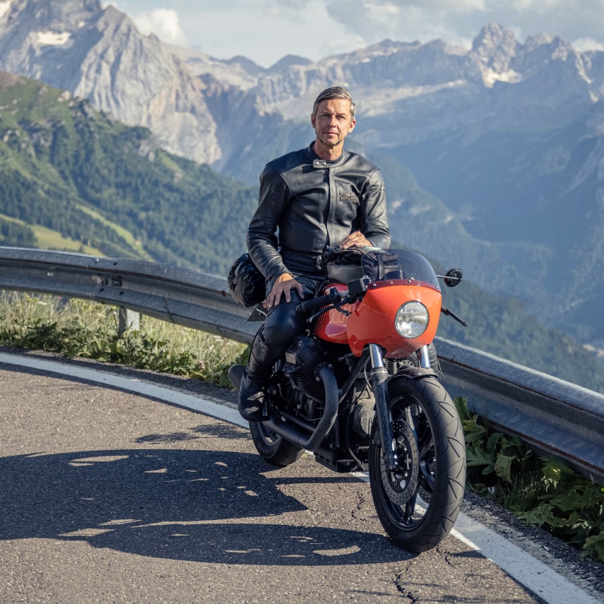 Axel Budde auf seinem roten Motorrad vor den Alpen