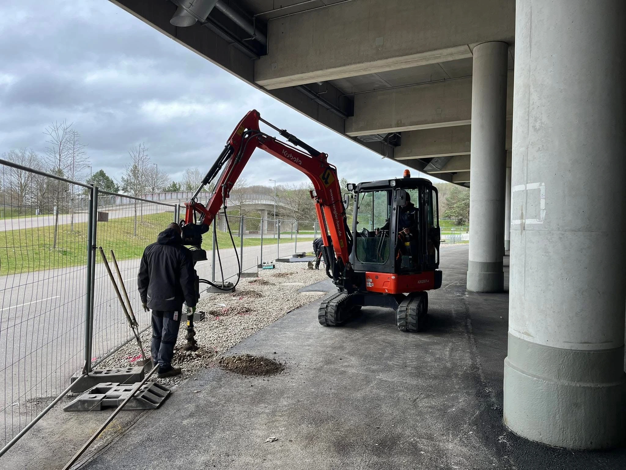 Minibagger-Einsatz beim Zaunbau unter Hochstraße
