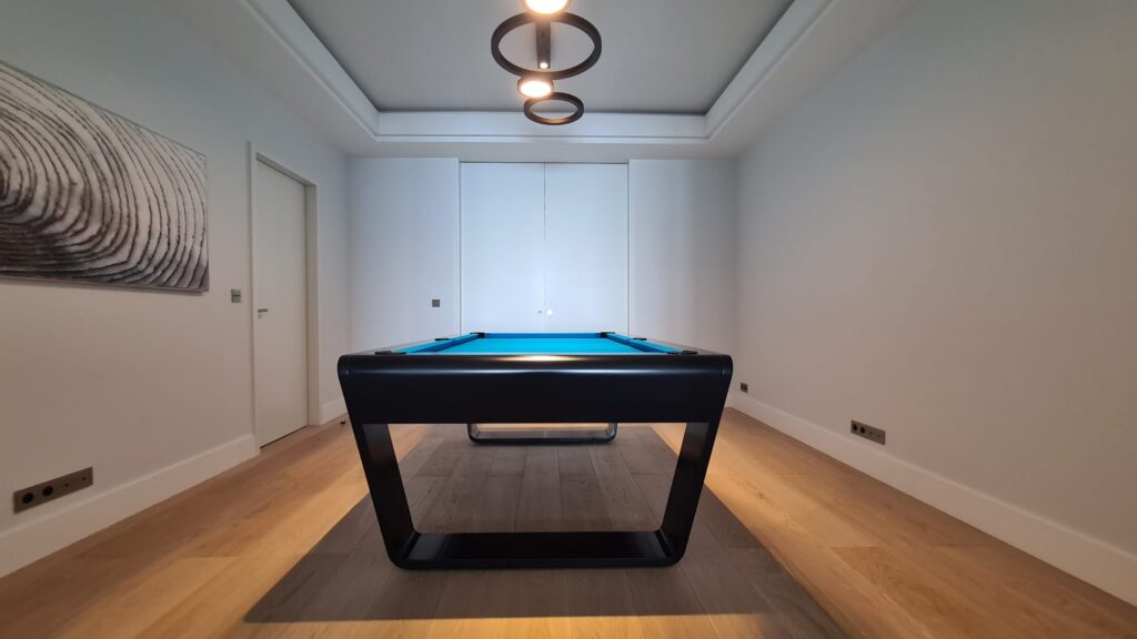 Schwarzer Luxus-Billardtisch mit blauem Tuch in minimalistischem Raum