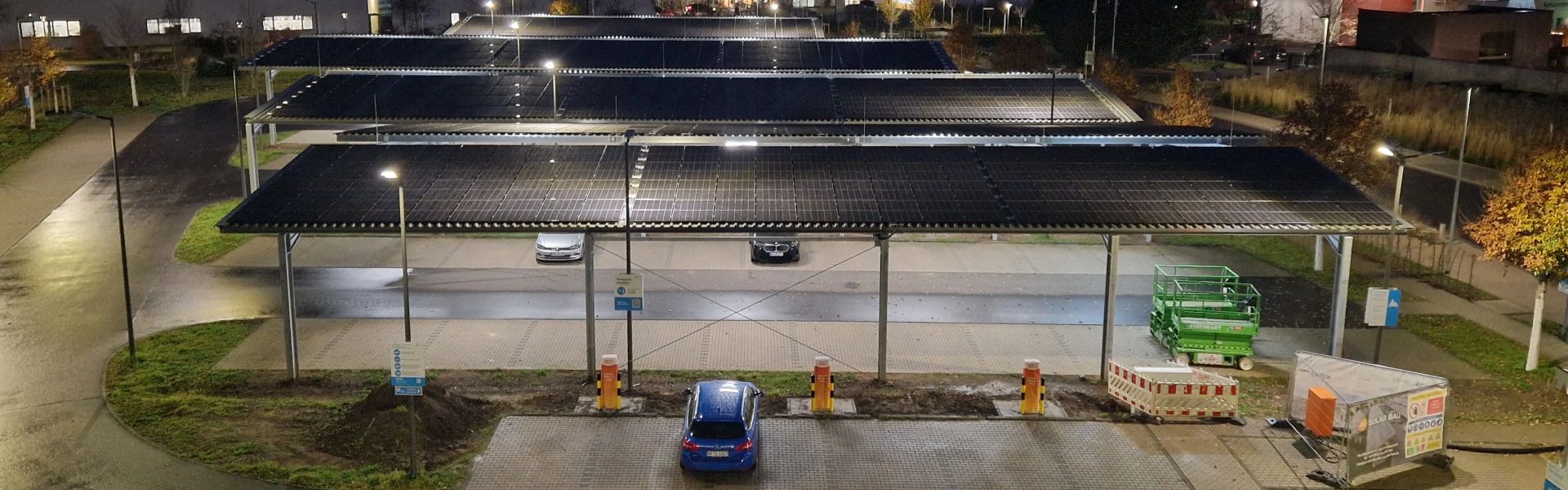 Solarüberdachter Parkplatz mit Ladeinfrastruktur bei Nacht