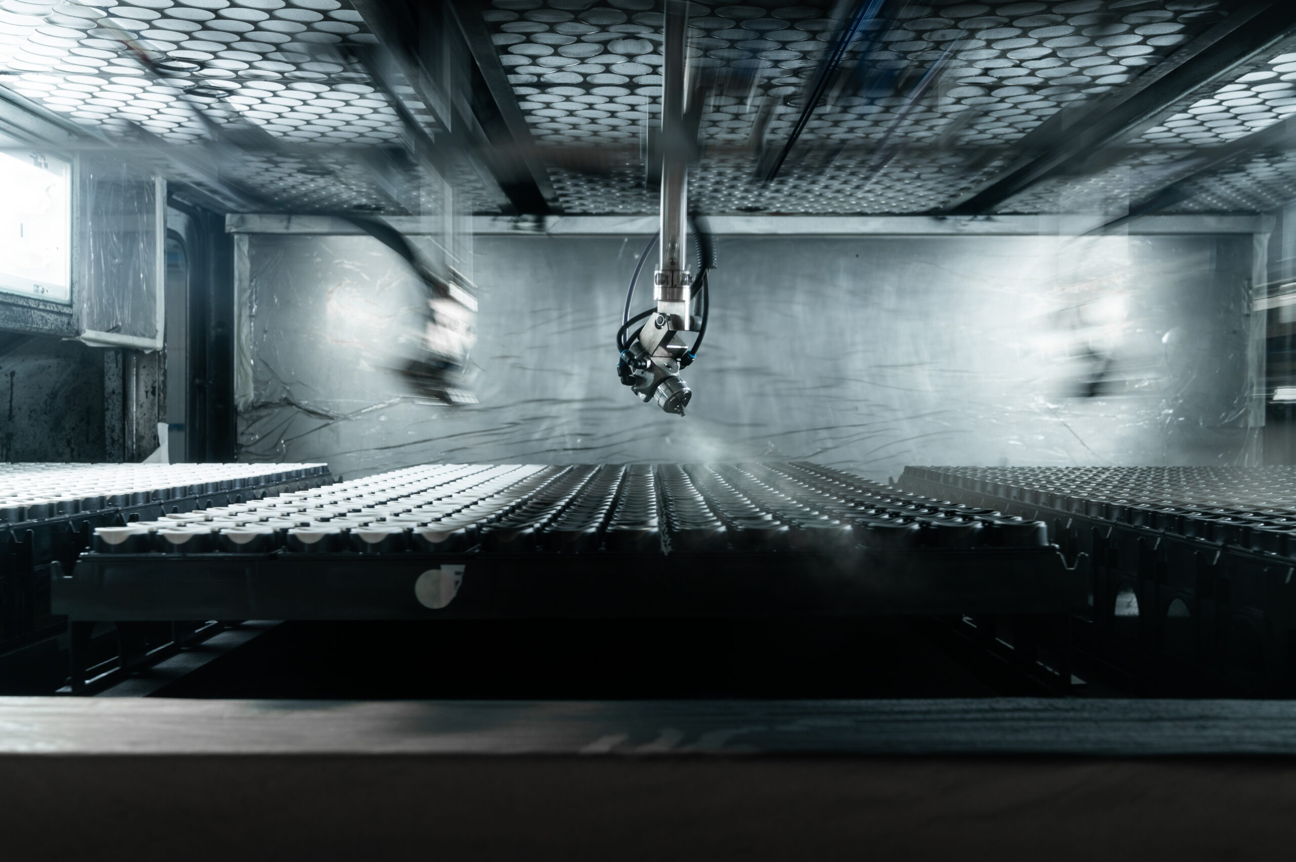 Industrieroboter über Warenträgern in der Anlagenhalle