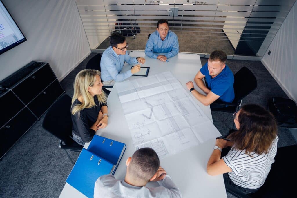 Team im Konferenzraum mit Bauplänen