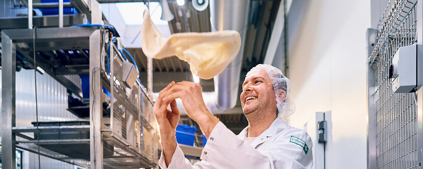 Mitarbeitender in der Pizzaproduktion