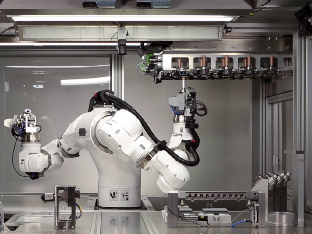 Roboterarm mit Bauteilen auf Fördersystem