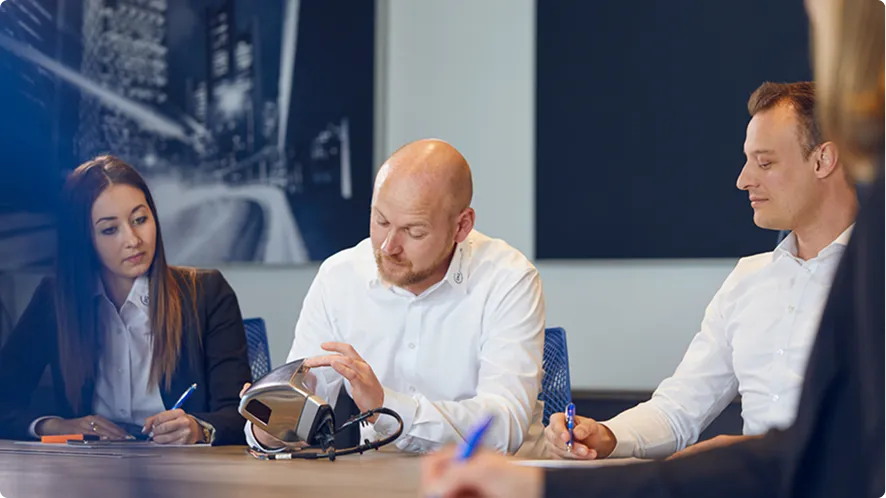 Spezialisten prüfen Automotive-Bauteil im Kundengespräch