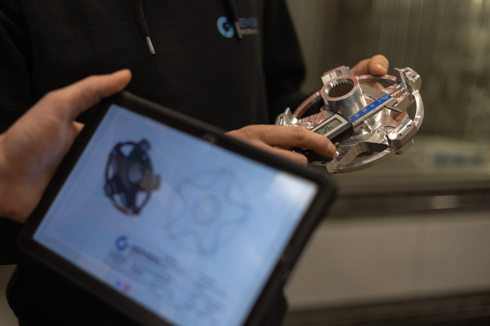 Mitarbeiter prüft Metallteil am Tablet