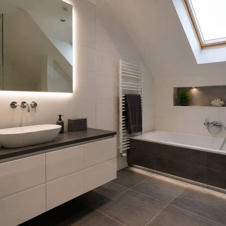 Modernes Badezimmer mit Waschtisch und Badewanne unter Dachschräge