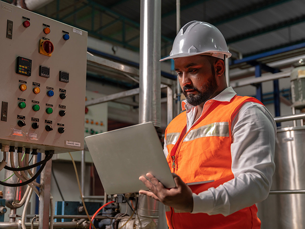 Elektrotechniker mit Laptop vor einer Anlage