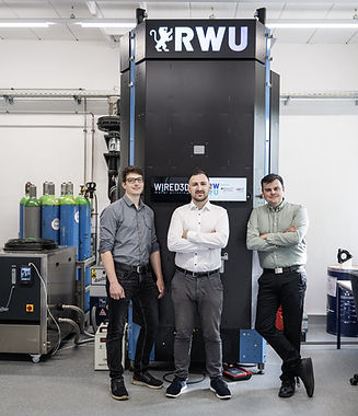 Gründer vor selbst entwickeltem DED-3D-Drucker