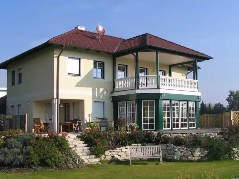 Zweigeschossiges Haus mit grünen Fensterrahmen