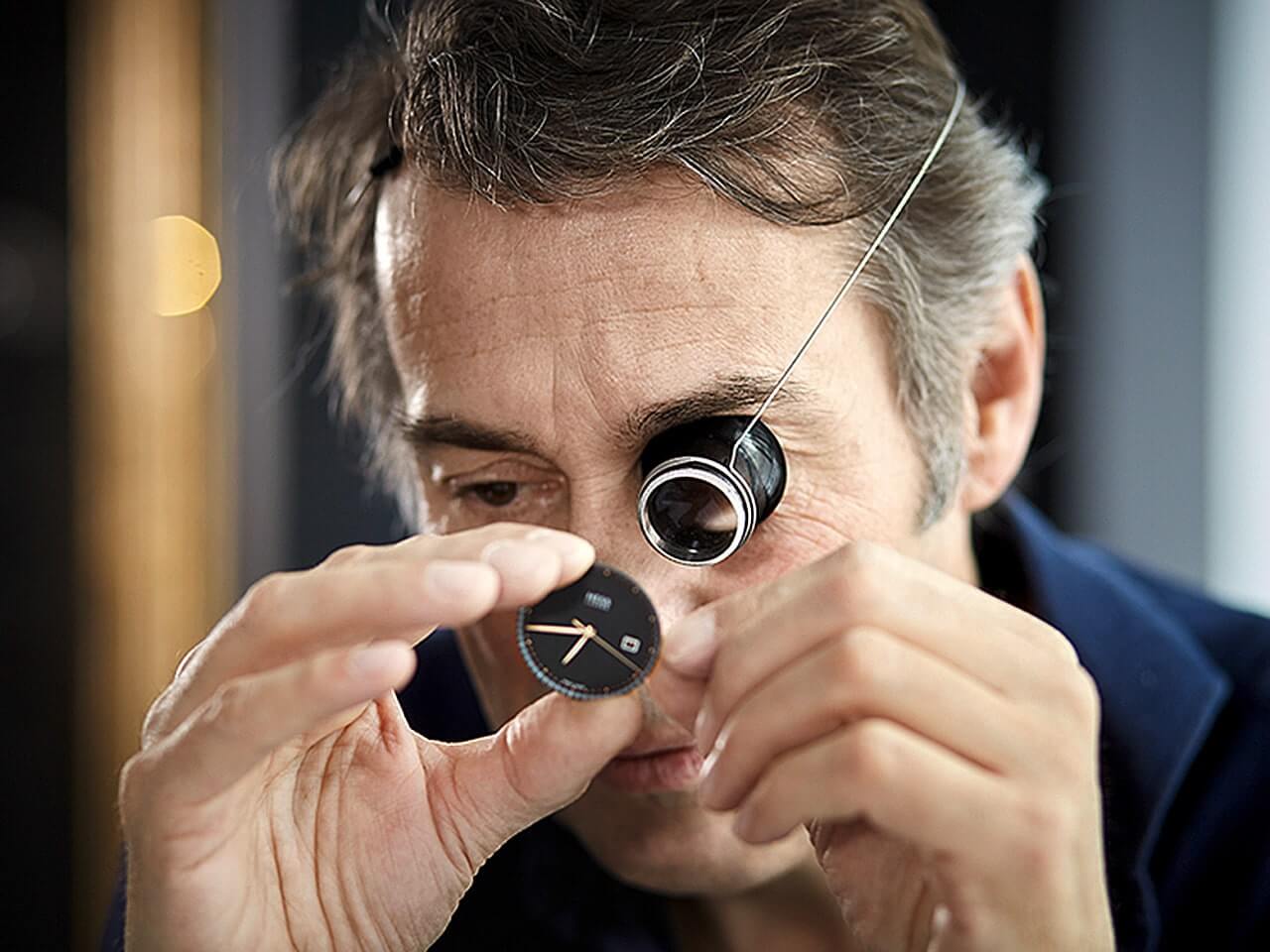 Uhrmacher Walter Hess arbeitet mit dem Okular an einem Zifferblatt