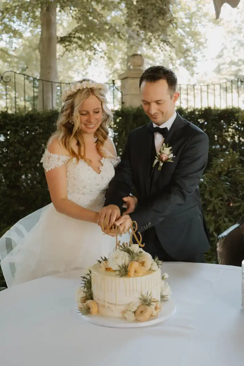 Brautpaar schneidet Hochzeitstorte mit Donuts und Blüten