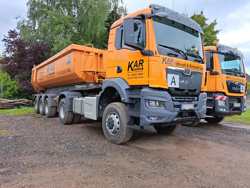 Orangefarbene Sattelzugmaschine mit Kippauflieger