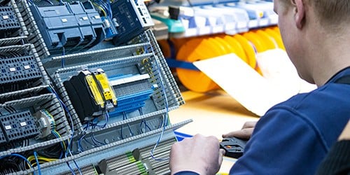 Mitarbeiter im Service steckt elektrische Verbindungen zusammen