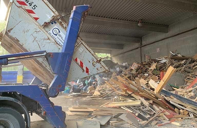 Muldenkipper kippt Holz auf einen Holzstapel