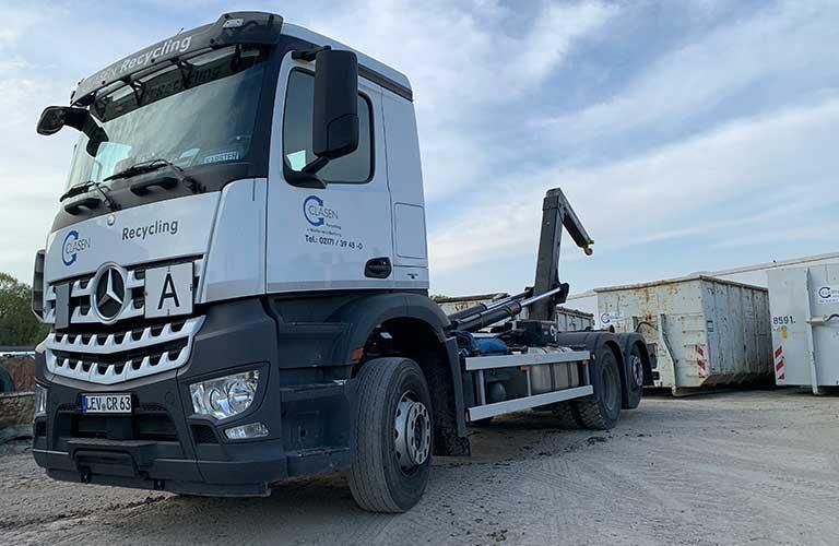 Lastwagen neben Müllcontainer auf dem Schotterplatz