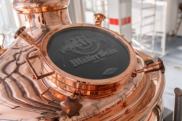 Kupferfarbener Braukessel mit Müller Bräu-Logo