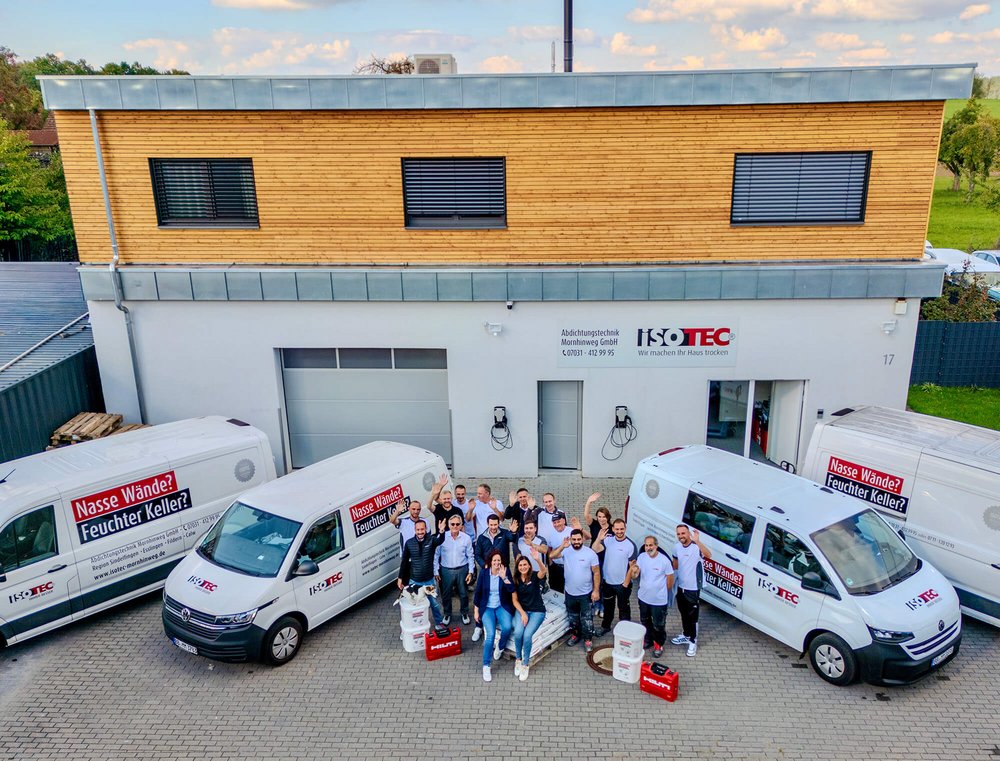 ISOTEC-Team vor Firmengebäude mit Servicefahrzeugen