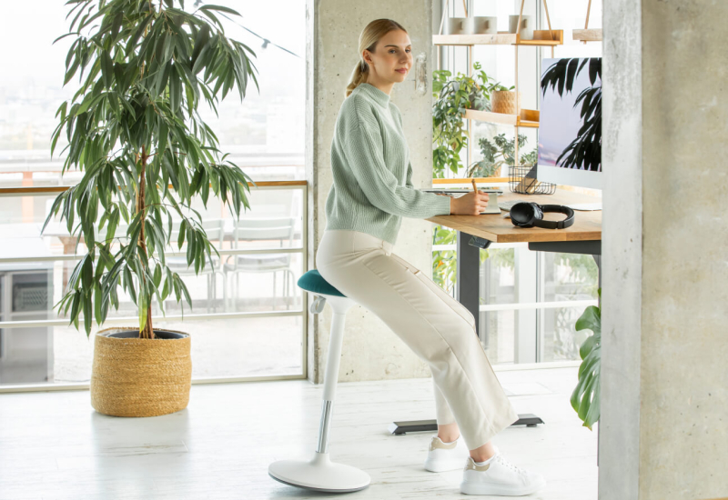 Arbeitsplatz mit höhenverstellbarem Schreibtisch und ergonomischem Stehhocker