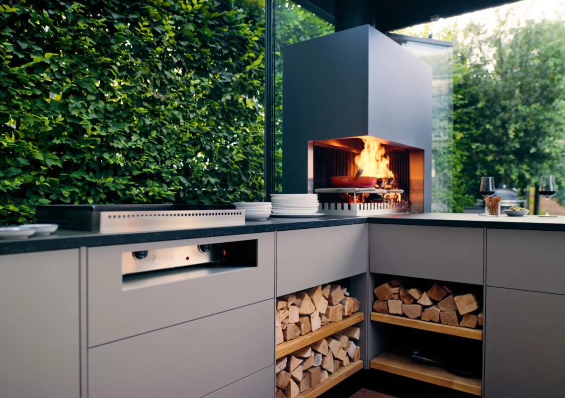 Ambienteküche in L-Form mit offenem Feuer und Plancha