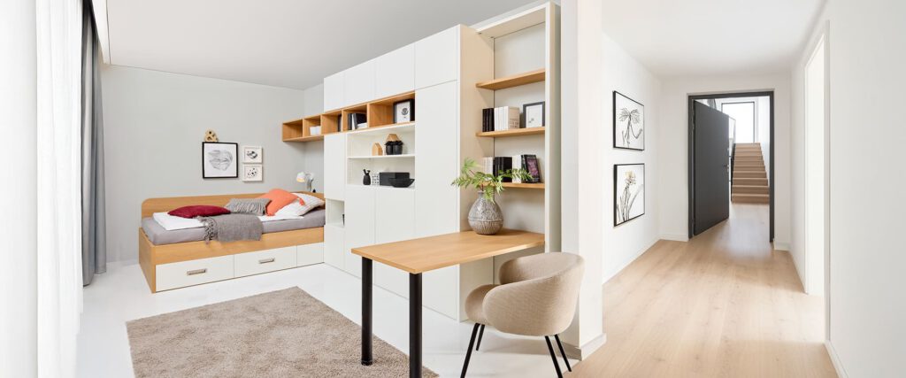 Gästezimmer mit Bett, Regal, Schränken und Tisch