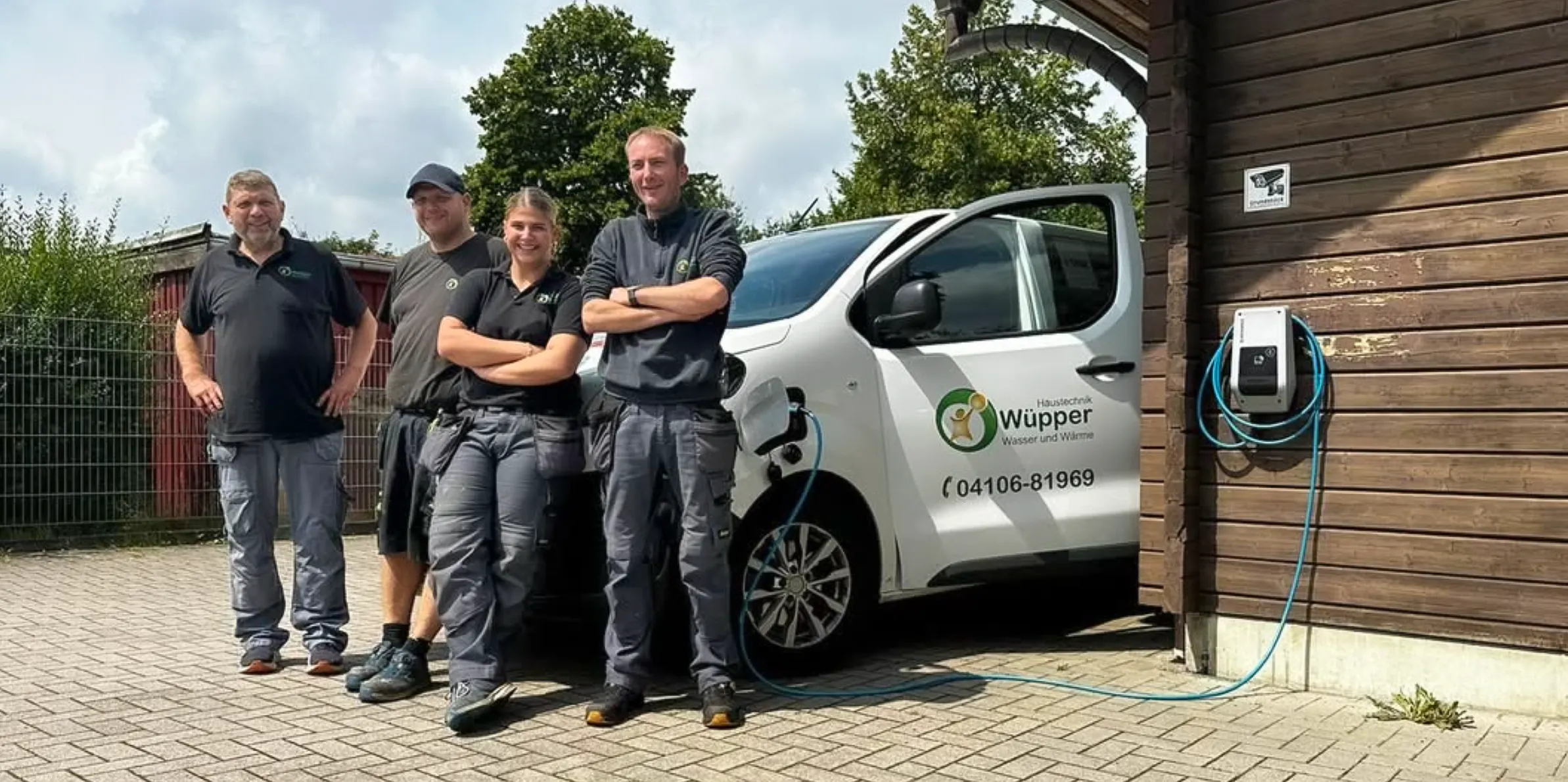 Team vor elektrisch betriebenem Servicefahrzeug an der Ladestation