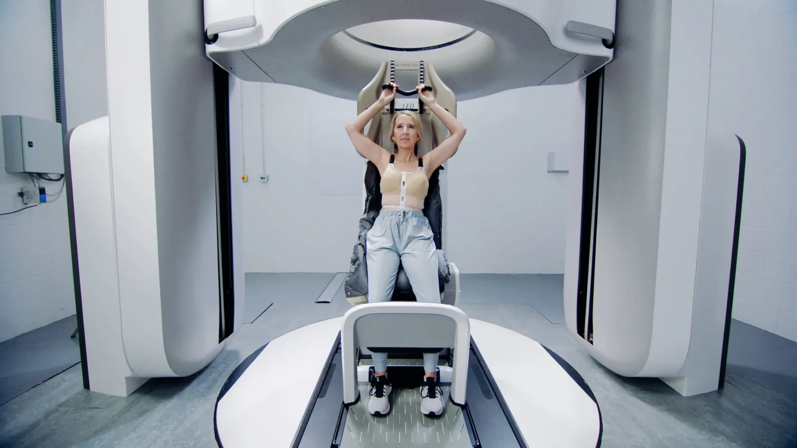 Patientin sitzt aufrecht im Leo-Cancer-Care-System unter dem Ring des Upright-CT