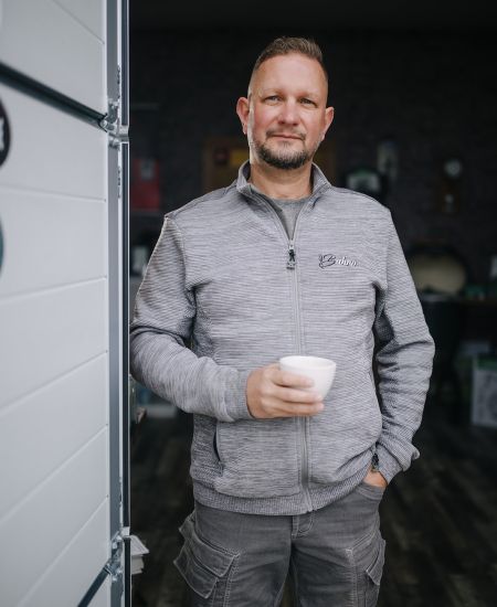 Mitarbeiter mit Kaffeetasse vor der Werkstatt
