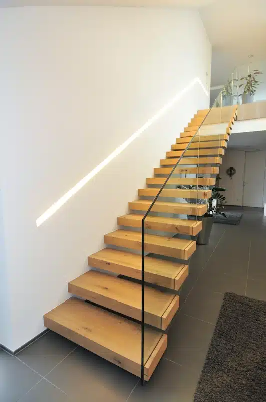 Kragarmtreppe mit Glasgeländer und beleuchtetem Handlauf
