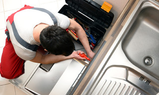Technician repairing a dishwasher in the kitchen