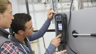 Anlagenmechaniker prüfen eine Anlage mit einem Messgerät