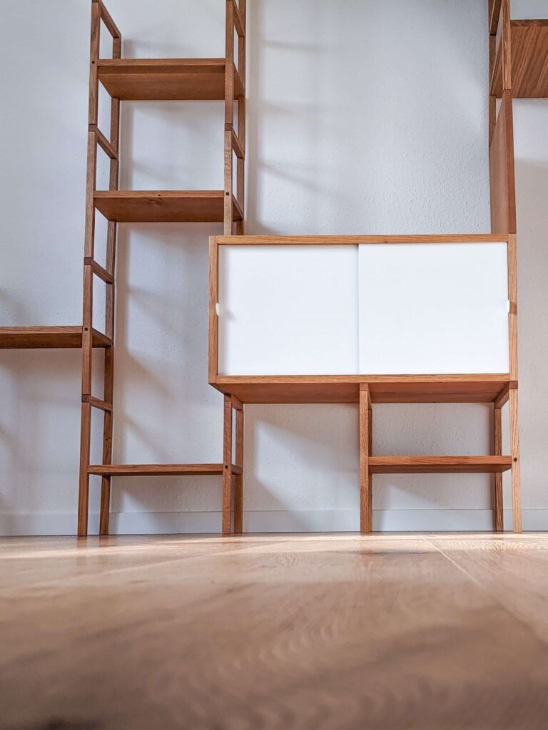 Holzregal mit Boxen und weissen Schiebetüren